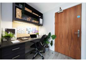 A study area with a desk, ergonomic chair, overhead shelving, storage drawers and integrated task lighting.