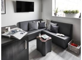 A lounge area with corner seating, a wall-mounted TV, small table and large window in a modern shared apartment.