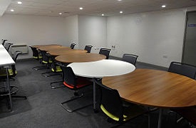 Social space showing a long table and 10 chairs, and another desk with three chairs