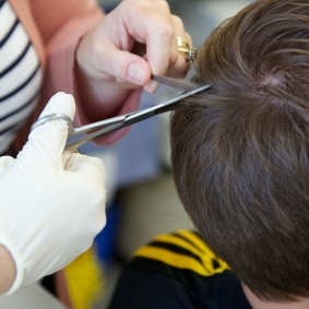 Someone cutting a strand of hair from a head