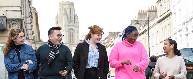 A group of students walk down Park Street in Bristol with the Wills Memorial Building in the background