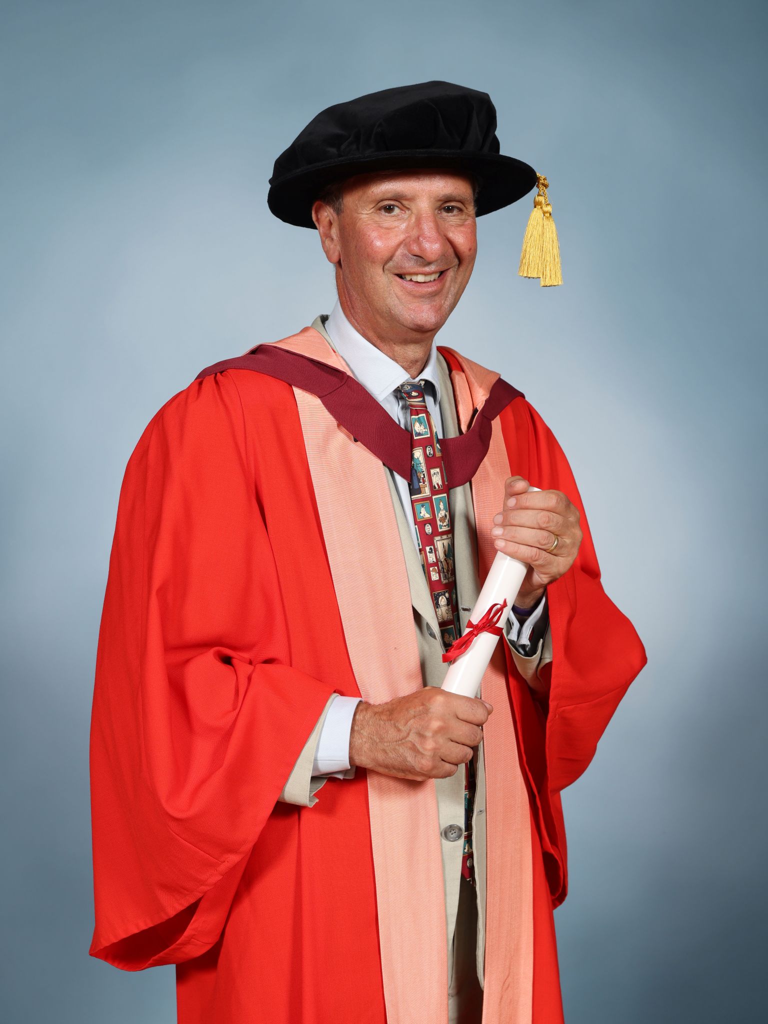 James Alexandroff wearing a mortar board and holding a parchment