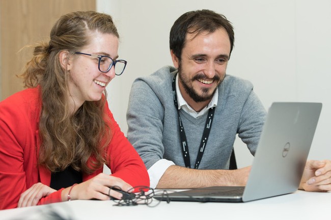 Two smiling people working together at laptop computer