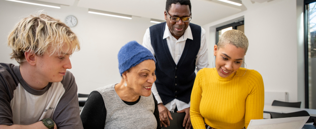 Three Black Humanities MA students studying documents in a classroom with their tutor