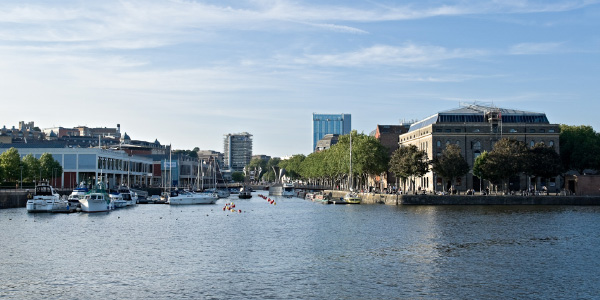 Bristol harborside in the sun, with the Cathedral on the left and boats docked in the foreground.