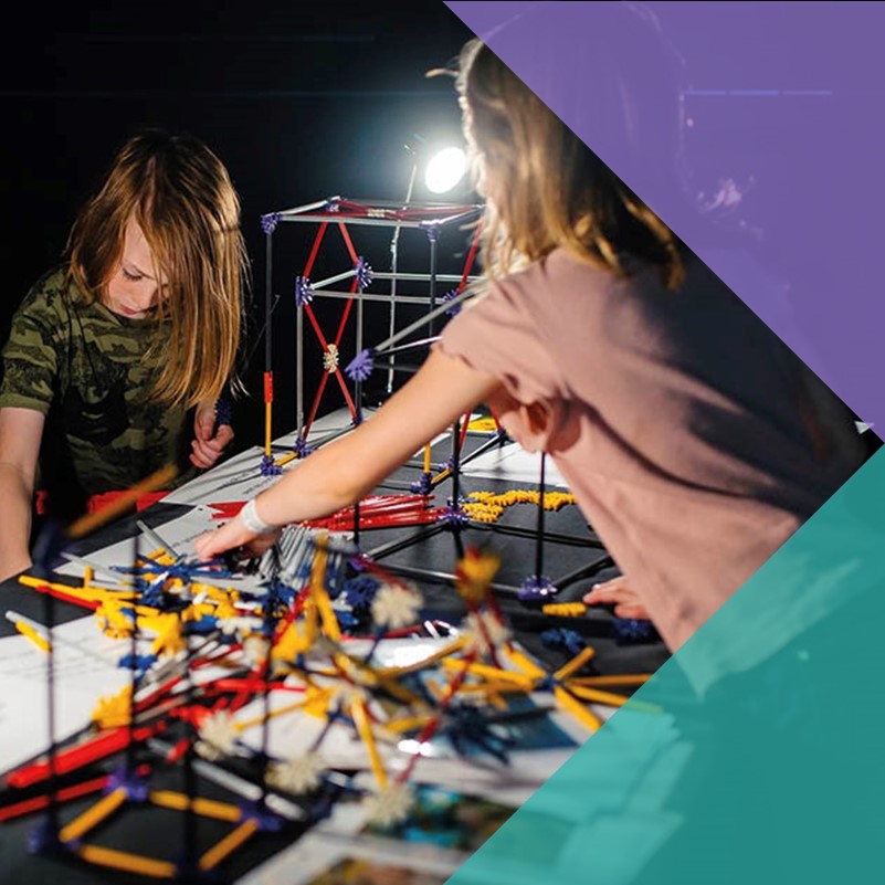 A photo of two children playing with plastic building toys with various papers on the table