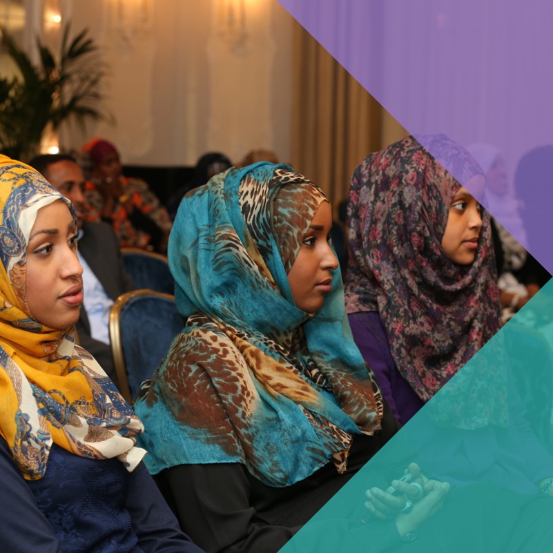 A photograph of three Somali women in traditional headdresses, sat at a town meeting