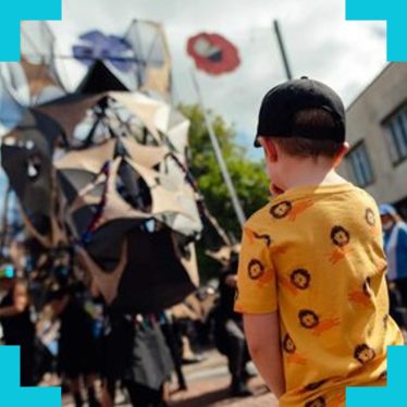 a small boy stood looking at the head of a 'life size' dragon puppet