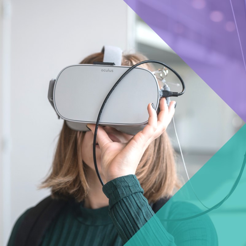 A photograph of a woman holding a virtual reality headset up to her eyes