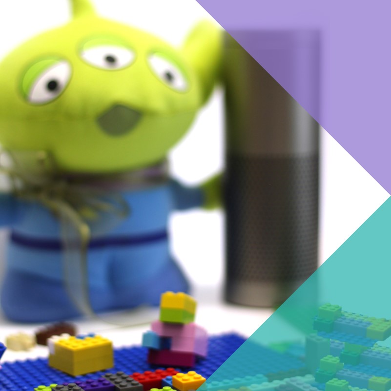 A photo showing Lego bricks is the foreground with a Toy Story alien toy and personal assistant device in the background