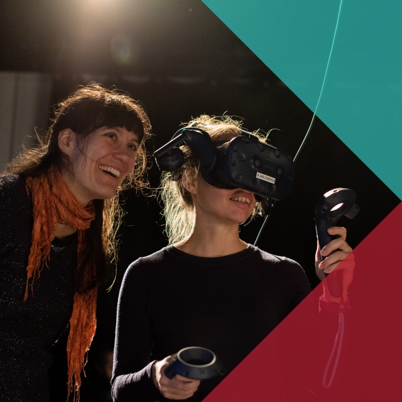 Two smiling women, one wearing a VR headset and holding two controllers