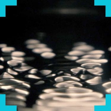 A close up image of liquid being disturbed by sound waves