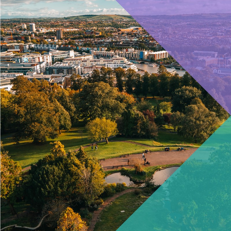 A aerial view of a city with a green park full of lush trees in the foreground
