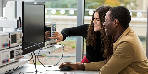 Two people in a meeting looking at a computer screen.