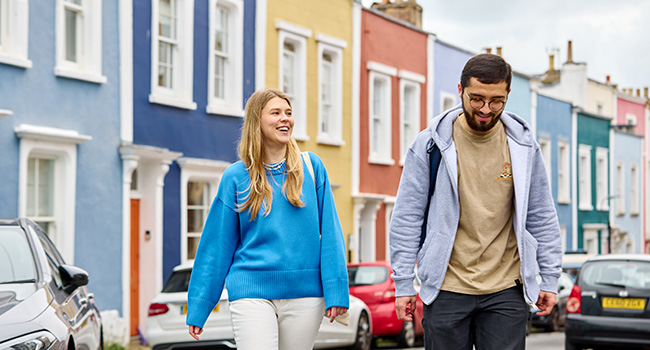 An image of two students walking in front of colourful painted houses in Clifton