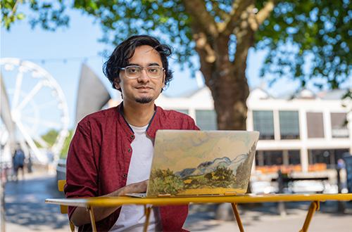 A student outside sitting at a laptop