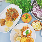 Image of two plates of curry, dish of sauce and dish of onions.