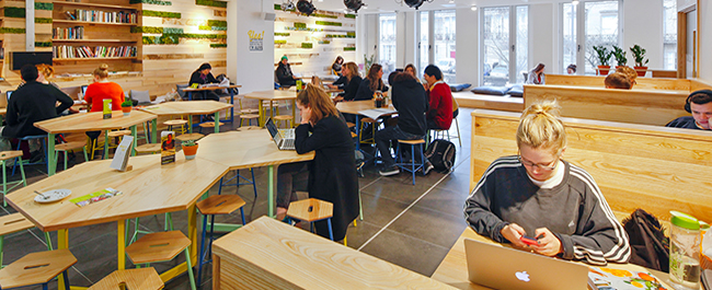 People sat at tables on their laptops and phones in a bar