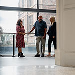 Three people stood in a large open room speaking to each other