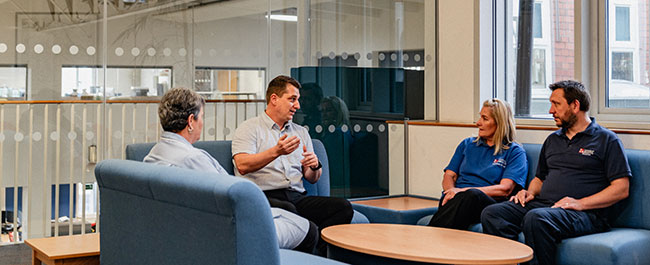 four people sat on sofas with one person leading the conversation