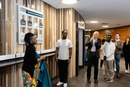 Photo showing attendees of the Inspirational Bristol Scientists 2023 celebration and Dean of Science, Jens Marklof, watching celebrants Lara and Shaun unveil the board.