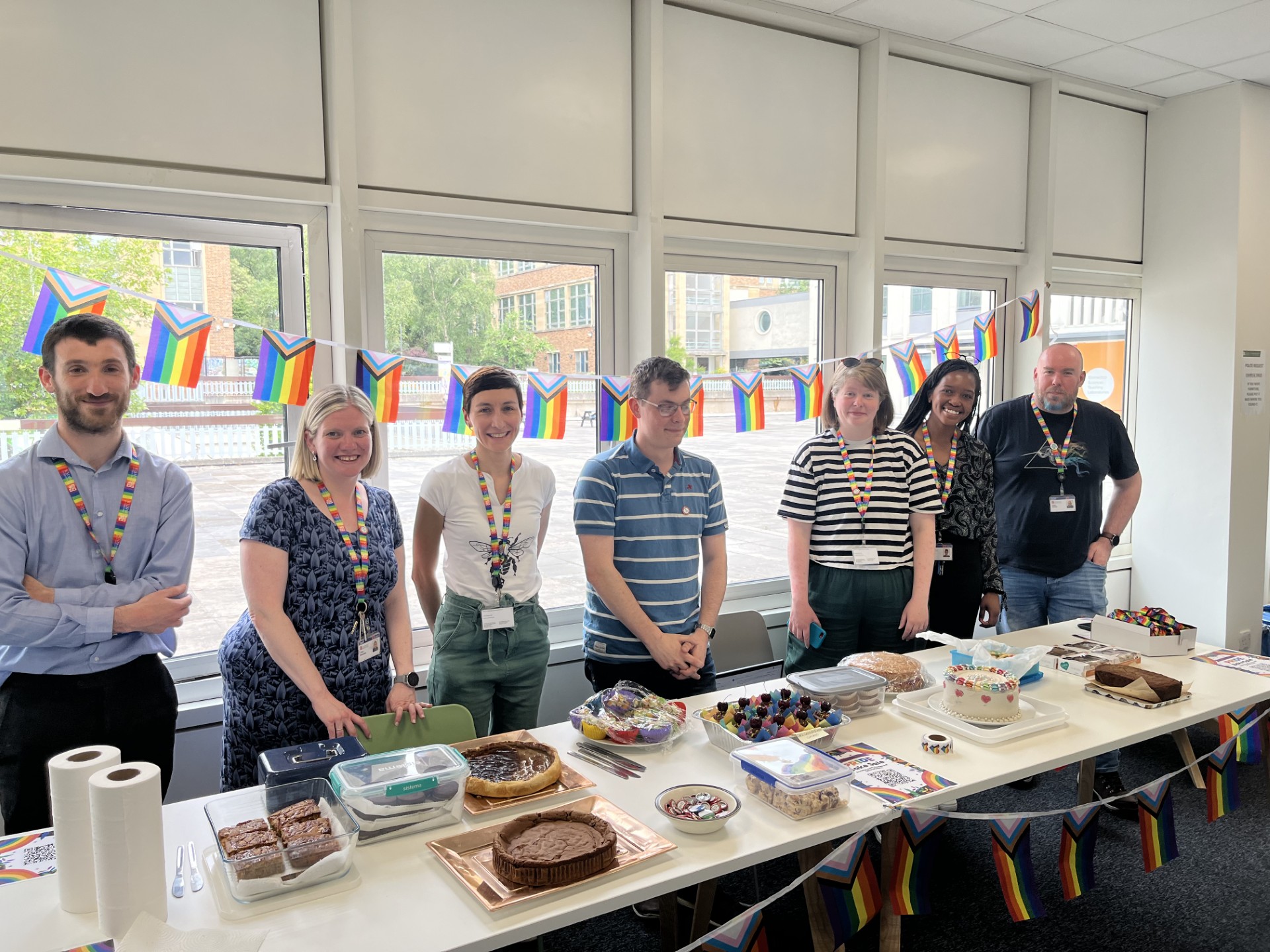 A group of people standing behind a table laid with cakes.