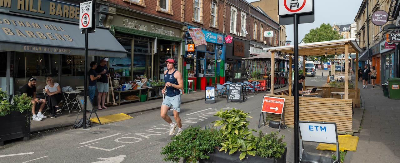 a pedestrianised street in cotham with cafes and outdoor seating on either side 