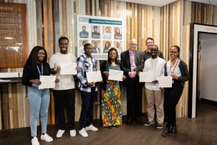 Photograph of 7 students holding paper certificates with the Dean of Science 