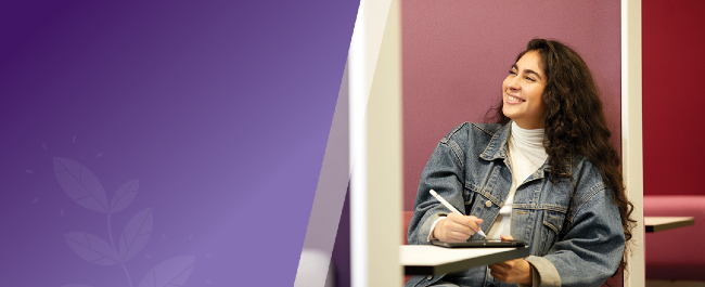 Image of person sitting on a table, holding a pen.