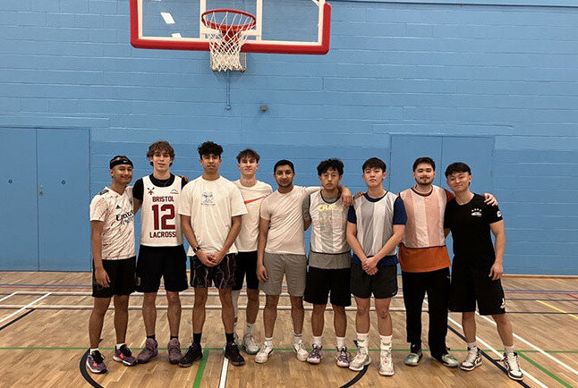 A group of students on a basketball court pose for a team photo
