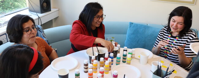 Three female students painting at a table