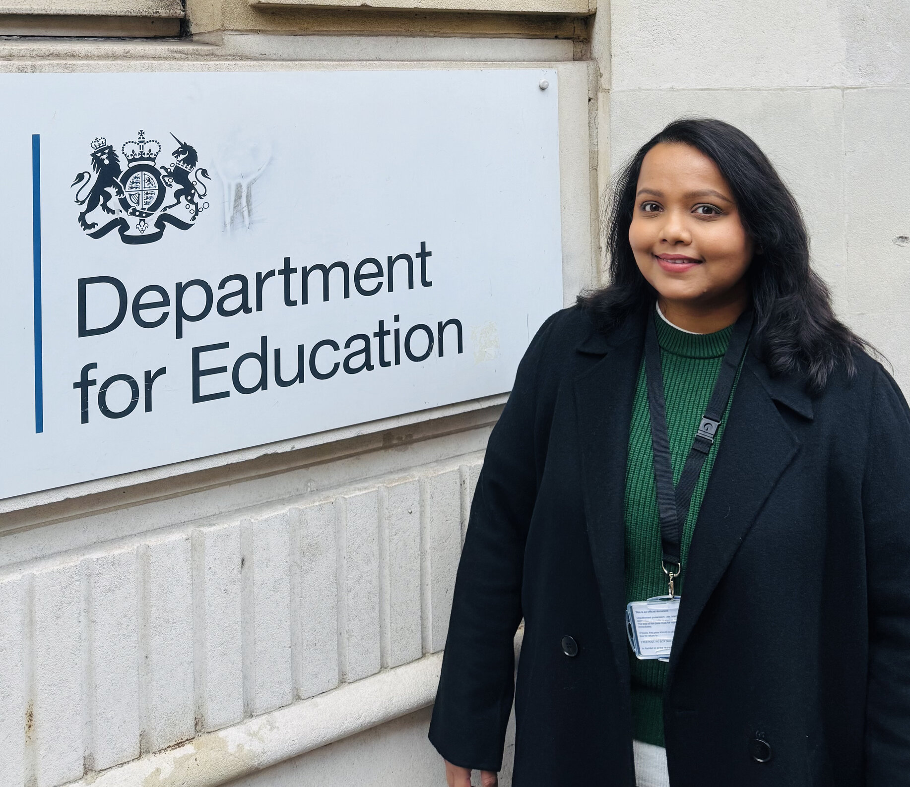 Female student standing in front of a black and white sign at the Department for Education