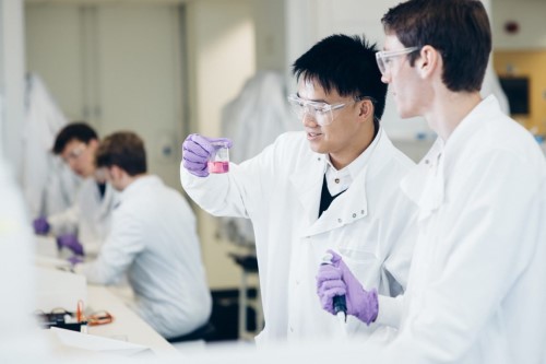 Student holding a beaker containing a colourful solution.