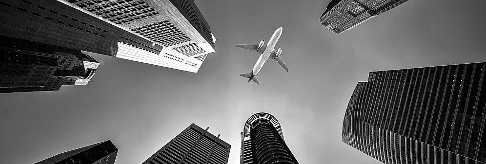 An airplane flying over some skyscrapers.
