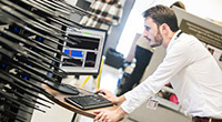 Man leaning over keyboard and monitor in communications lab