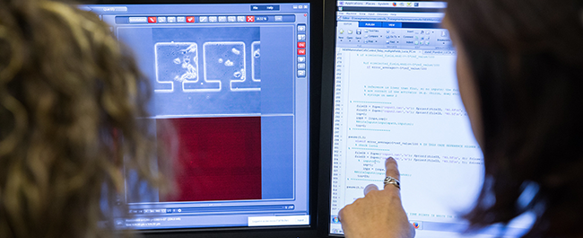 Two women in front of screens of code