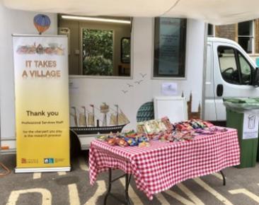 A table with a red and white picnic-style tablecloth, containing various snacks, displayed outside the TARG van, with a big sign saying