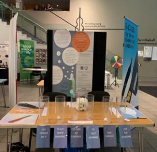 A research display, with a line of tubes on a table that people can use to vote to indicate their reasons for smoking cigarettes