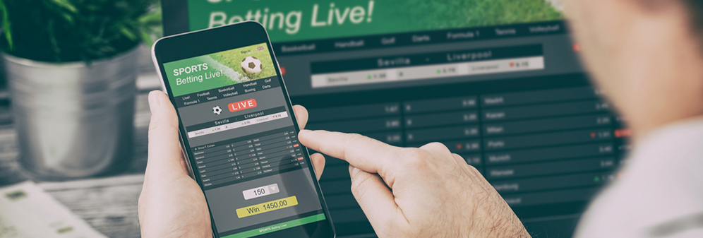 a person using a sports betting app on a phone and laptop