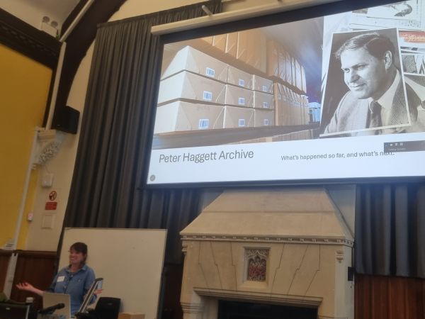 Speaker at celebration event with image of archive contents