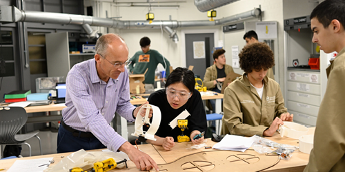 A teacher working with students on an engineering project.