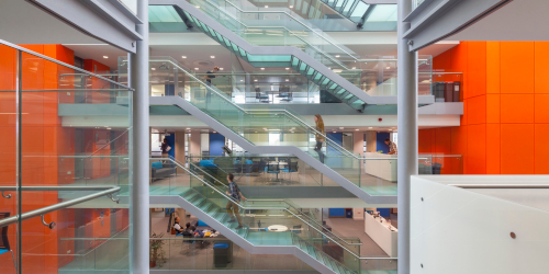 People walking up and down the staircases in the glass atrium at the Life Sciences Building