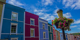 A row of terraced houses, painted in different bright colours, on Ambrose Road in Hotwells, Bristol.