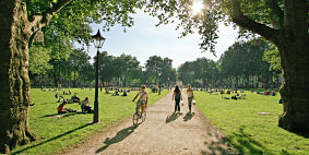 People cycling, walking and sitting in Queen Square in Bristol on a sunny day.