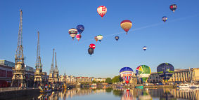 Hot air balloons taking off from and flying over Bristol Harbourside.