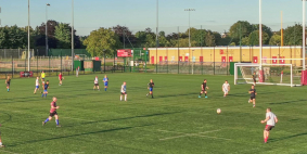 Several players enjoying a game of football on a large grass pitch