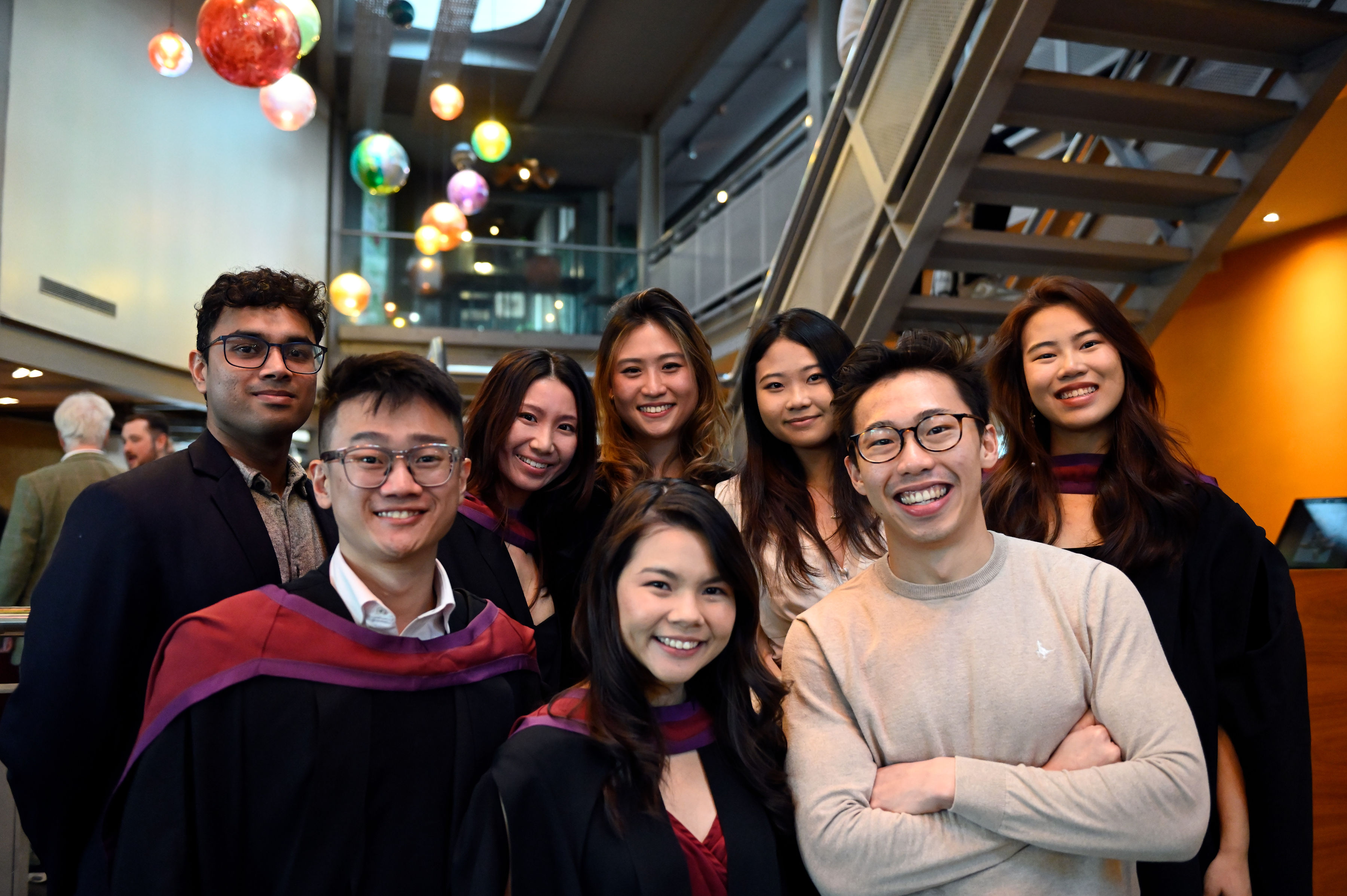 group of male and female law students attending the February graduation, some with graduation gowns on and smiling.