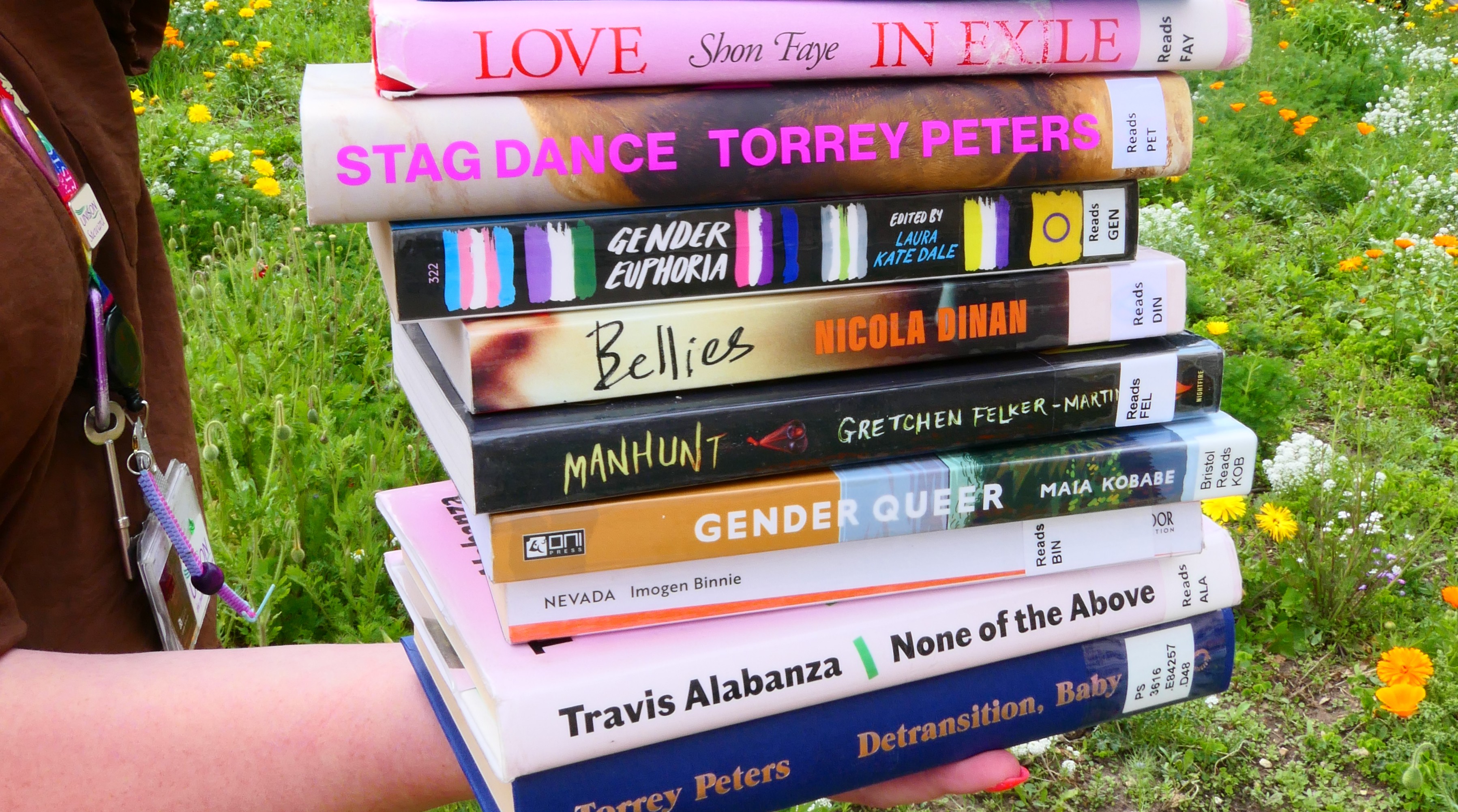 A stack of books about trans-ness or by transgender authors. Some titles include Love in Exile by Shon Faye, Bellies by Nicola Dinan, and Nevada by Imogen Binnie.