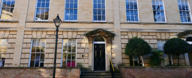 The outside of the Education library. The building is light stone and has lots of windows and a grand front door.