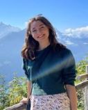 Dr Watson standing on a balcony with mountains behind her smiling